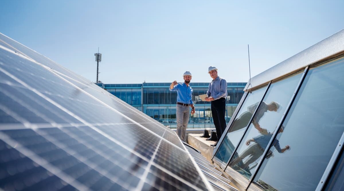 Zwei Energieexperten erörtern auf einem Solardach die Umsetzung nachhaltiger Energiekonzepte.